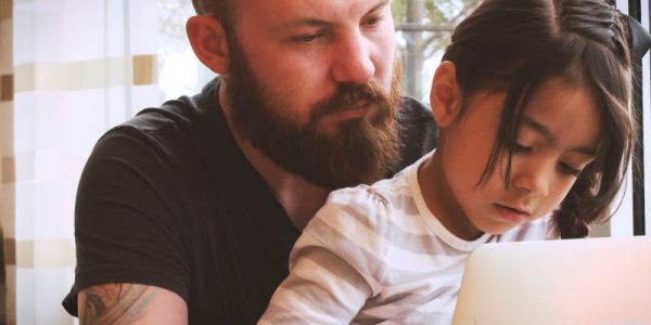 A man and a girl sit at a laptop together.