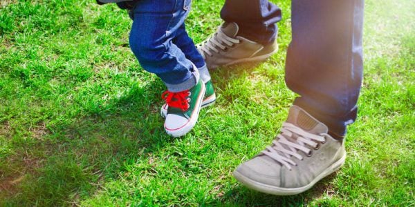 A child and an adult wearing trainers on grass