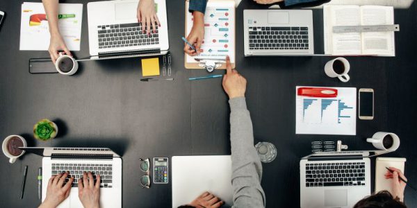 Five colleagues working together using laptops and taking notes