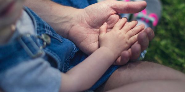 A child puts their hand into an adult's hand