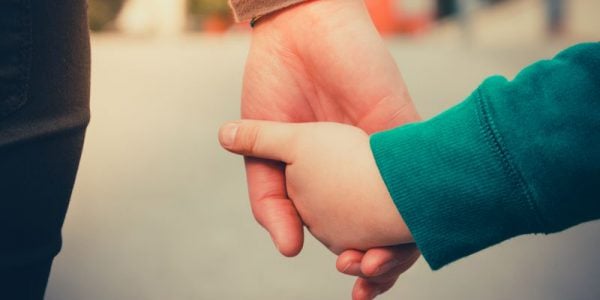 A child and an adult hand-in-hand