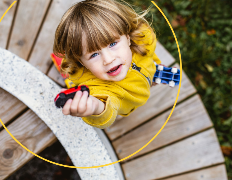 A child reaching up holding a toy car