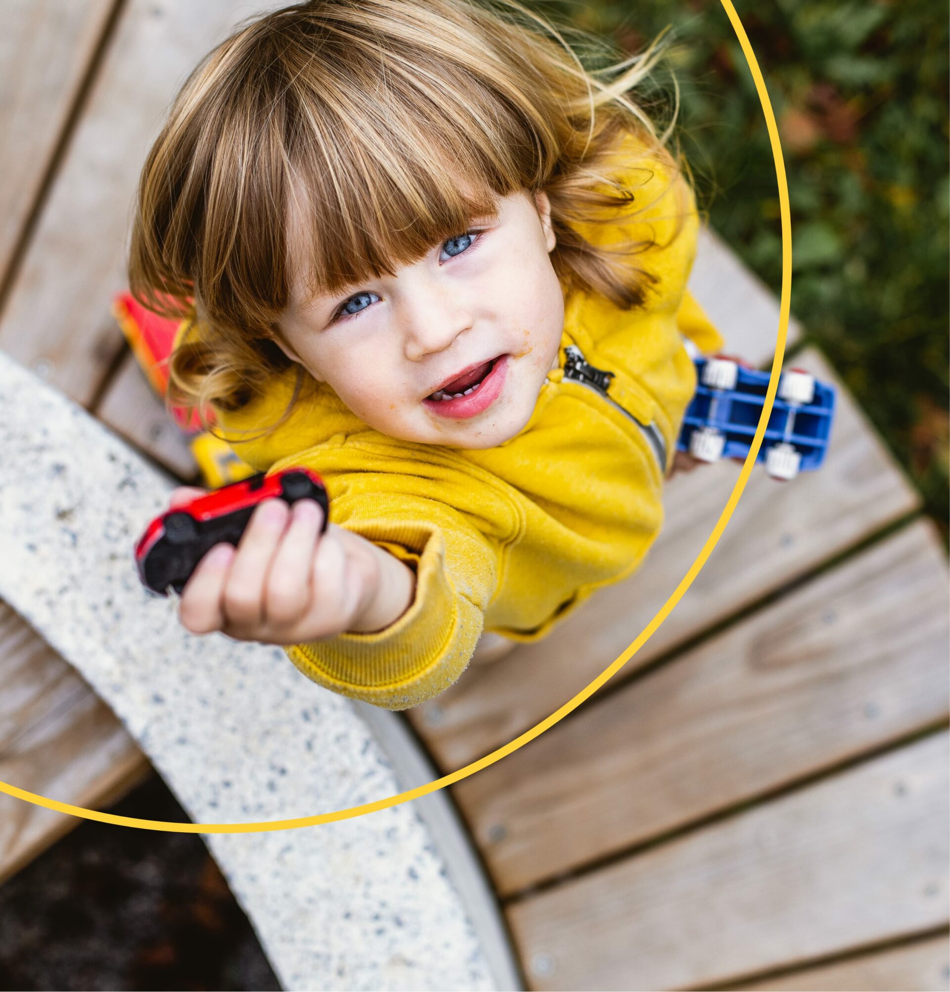 A child reaches up holding a toy car