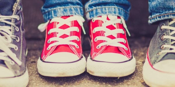 Teenagers' feet in a row wearing pink and blue trainers.